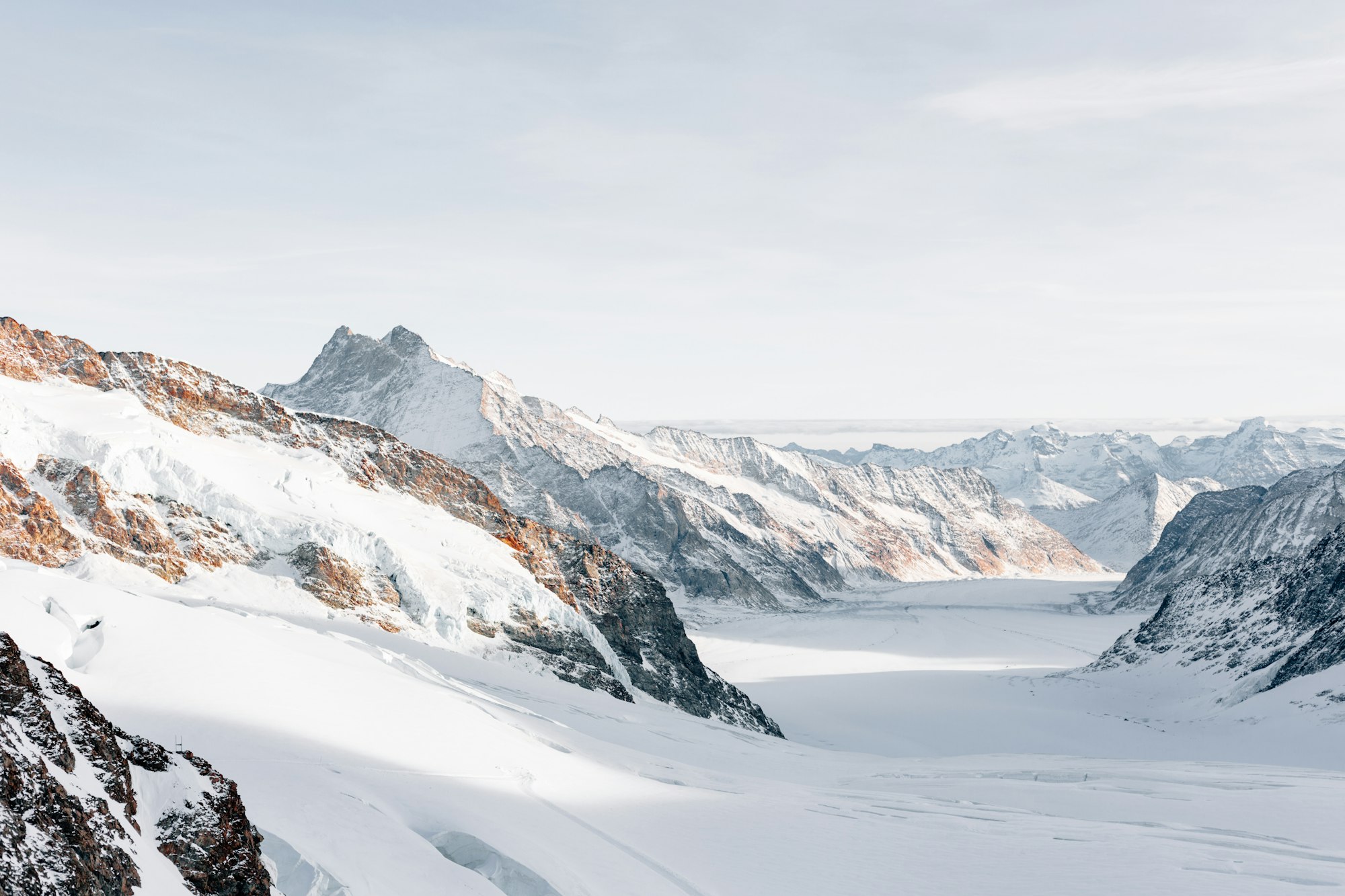 A snowy mountainous landscape with a clear view to the horizon.